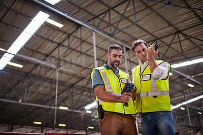Buy stock photo Low angle shot of two warehouse workers standing in a large warehouse