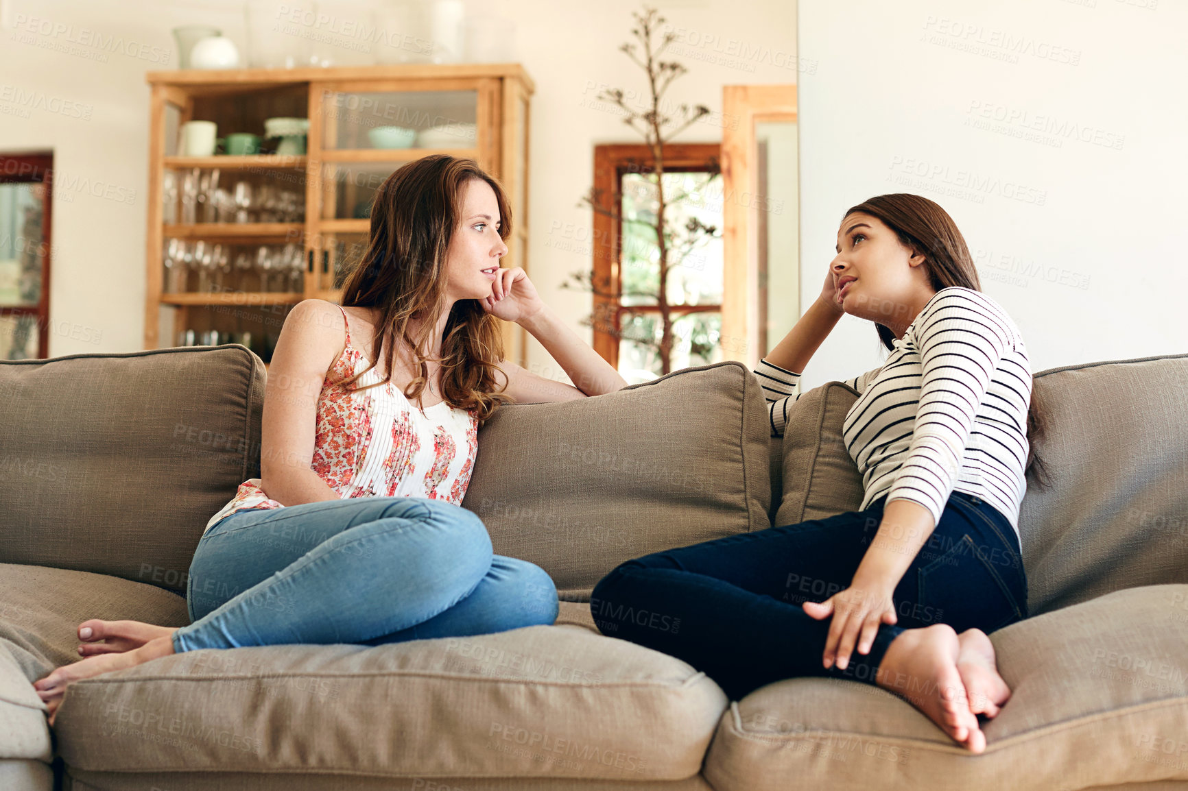 Buy stock photo Shot of two friends talking together while sitting on the sofa at home