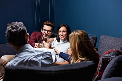 Buy stock photo Shot of a group of friends making a toast while enjoying a night in together at home