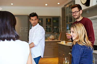 Buy stock photo Shot of a group of friends talking and drinking wine together while preparing dinner