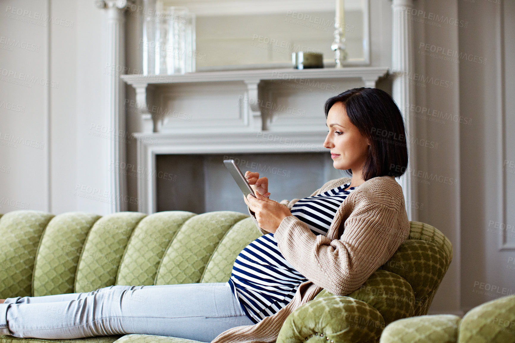 Buy stock photo Pregnant, woman and scroll on couch with tablet, research or digital app for growth of unborn child. Person, pregnancy and reading in home with tech, motherhood blog or check fetal development online