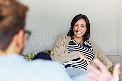 Buy stock photo Shot of a young expecting couple talking together while sitting on the sofa at home
