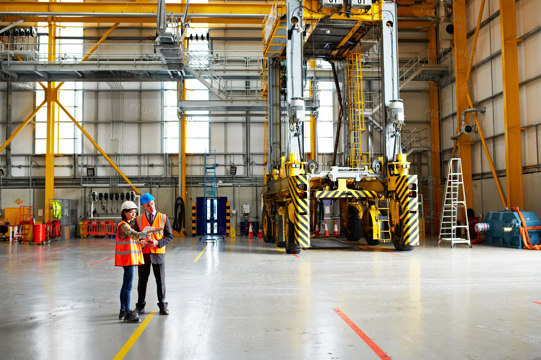 Buy stock photo Shot of two warehouse workers talking together over a digital tablet