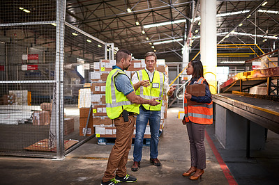 Buy stock photo Shot of three workers shaking hands together while standing in a large warehouse