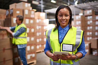 Buy stock photo Portrait of a worker using a digital tablet in a large warehouse full of boxes with a colleague in the background
