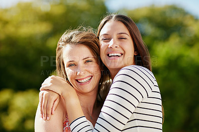 Buy stock photo Portrait of two young friends hugging while enjoying a day outside together