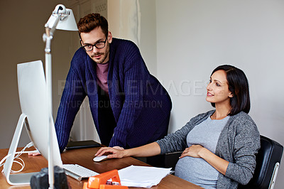 Buy stock photo Shot of a pregnant woman and her husband talking together in their home office