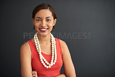 Buy stock photo Studio portrait of a smiling young woman standing with her arms crossed against a gray background