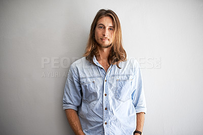Buy stock photo Studio portrait of a young man standing with his hands in his pockets against a gray background
