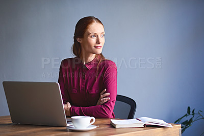 Buy stock photo Shot of a young woman deep in thought while working on a laptop in an office