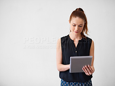 Buy stock photo Studio shot of a young woman using a digital tablet against a gray background