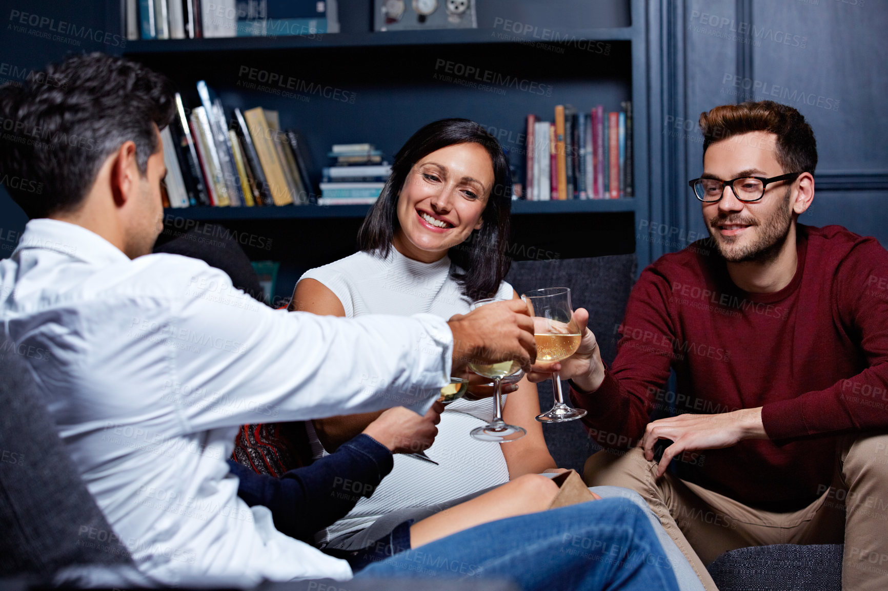 Buy stock photo Shot of a group of friends making a toast while enjoying a night in together at home