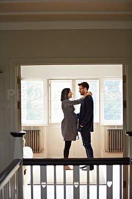 Buy stock photo Shot of a happy pregnant couple standing face to face together in their home