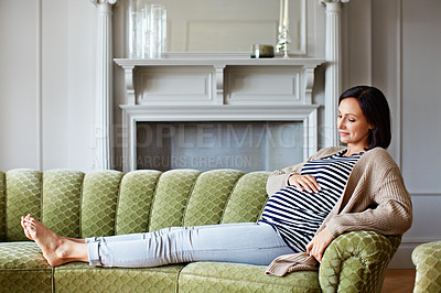 Buy stock photo Shot of a young pregnant woman relaxing on her sofa