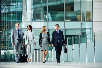 Buy stock photo Shot of businesspeople talking together while walking in the lobby of an office building