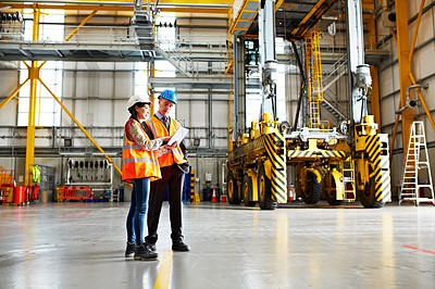 Buy stock photo Shot of two warehouse workers talking together over a digital tablet