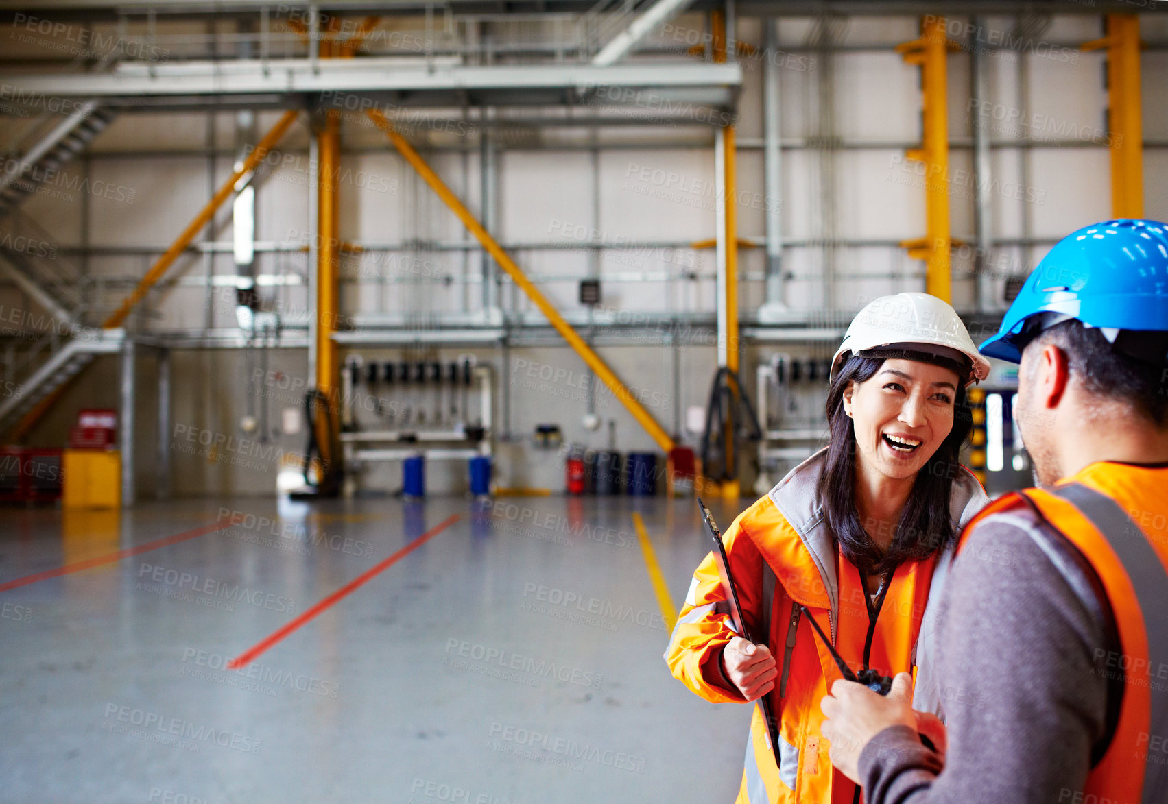 Buy stock photo Shot of two workers talking together while standing in a warehouse
