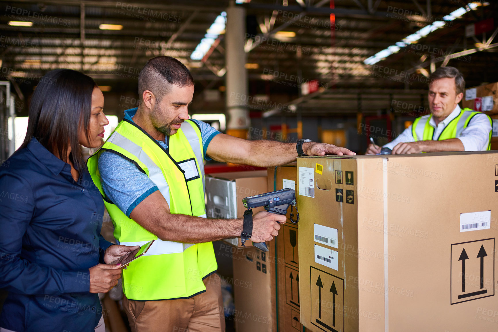 Buy stock photo Shot of workers scanning boxes with a barcode reader while working inside a large warehouse