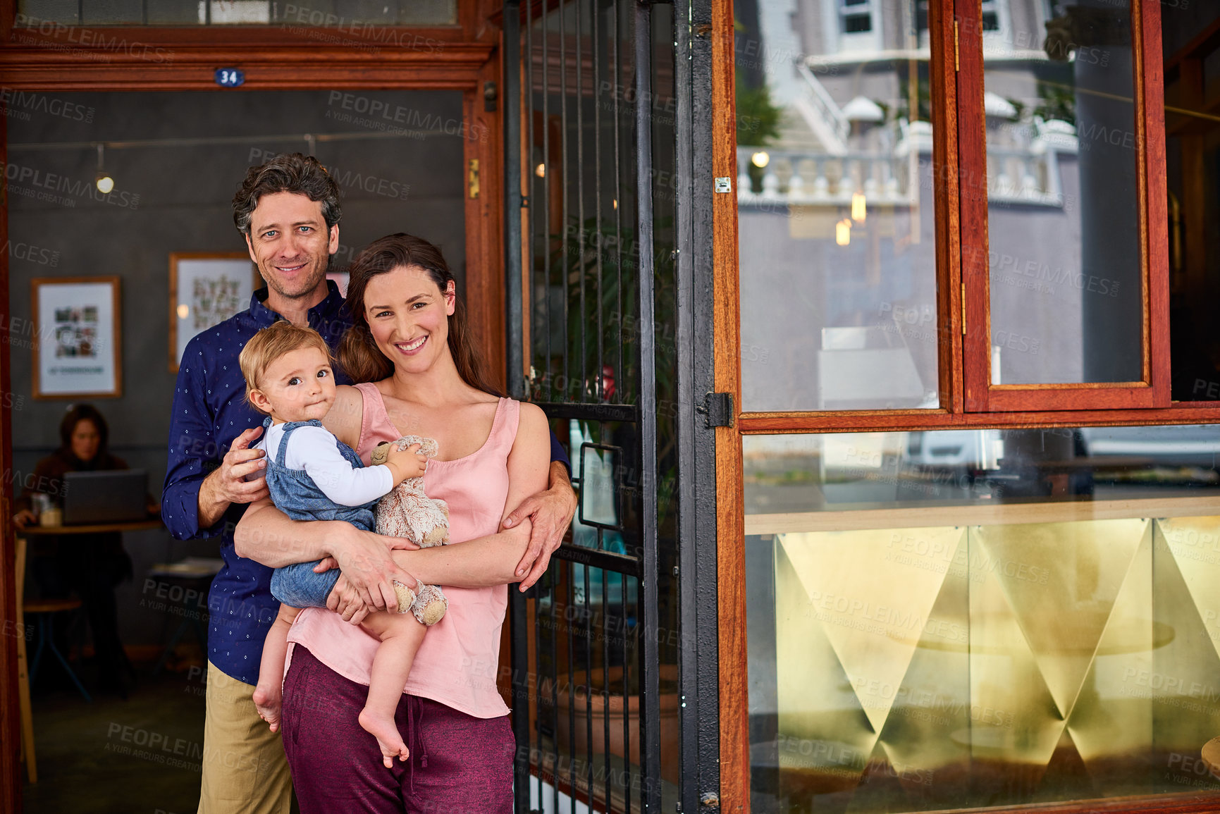 Buy stock photo Portrait of smiling couple and their little girl standing in front of their bakery