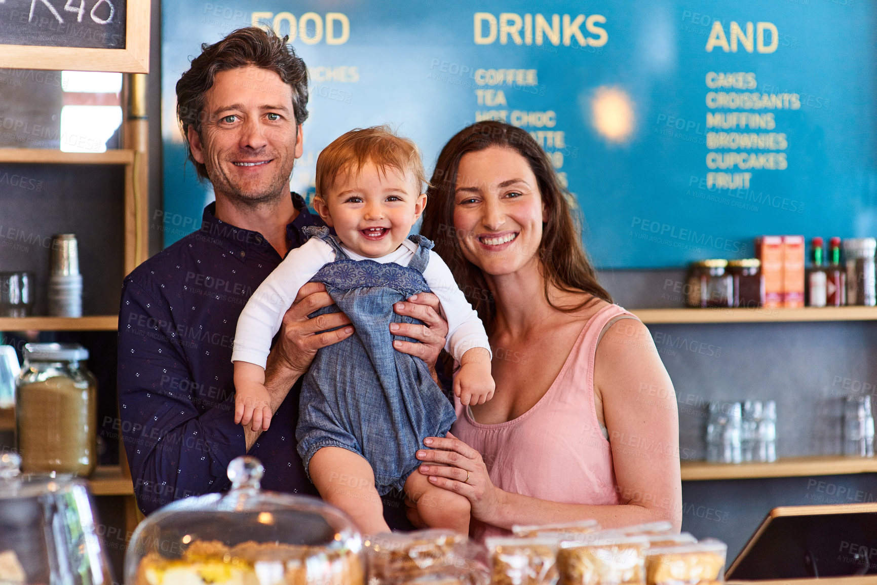Buy stock photo Portrait of smiling couple and their little girl standing in their bakery