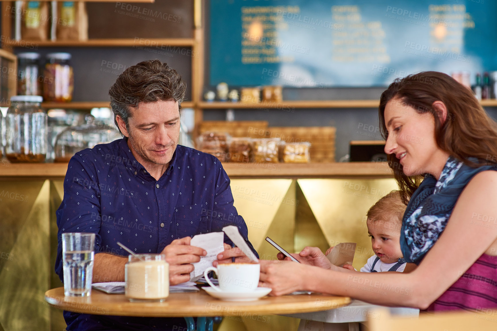 Buy stock photo Shot of a couple and their baby daughter sitting at a table in a cafe