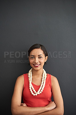 Buy stock photo Studio portrait of a smiling young woman standing with her arms crossed against a gray background