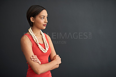Buy stock photo Studio shot of a focused young woman standing with her arms crossed against a gray background