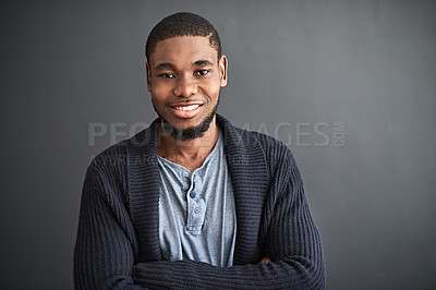 Buy stock photo Studio portrait of a smiling young man standing with his arms crossed against a gray background