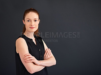 Buy stock photo Studio portrait of a focused young woman standing with her arms crossed against a gray background