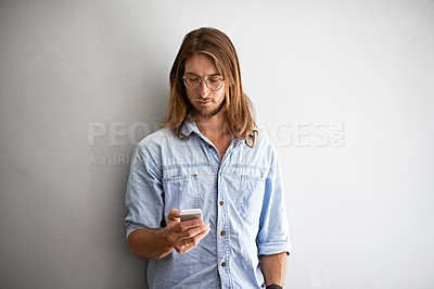 Buy stock photo Studio shot of a young man using a cellphone against a gray background