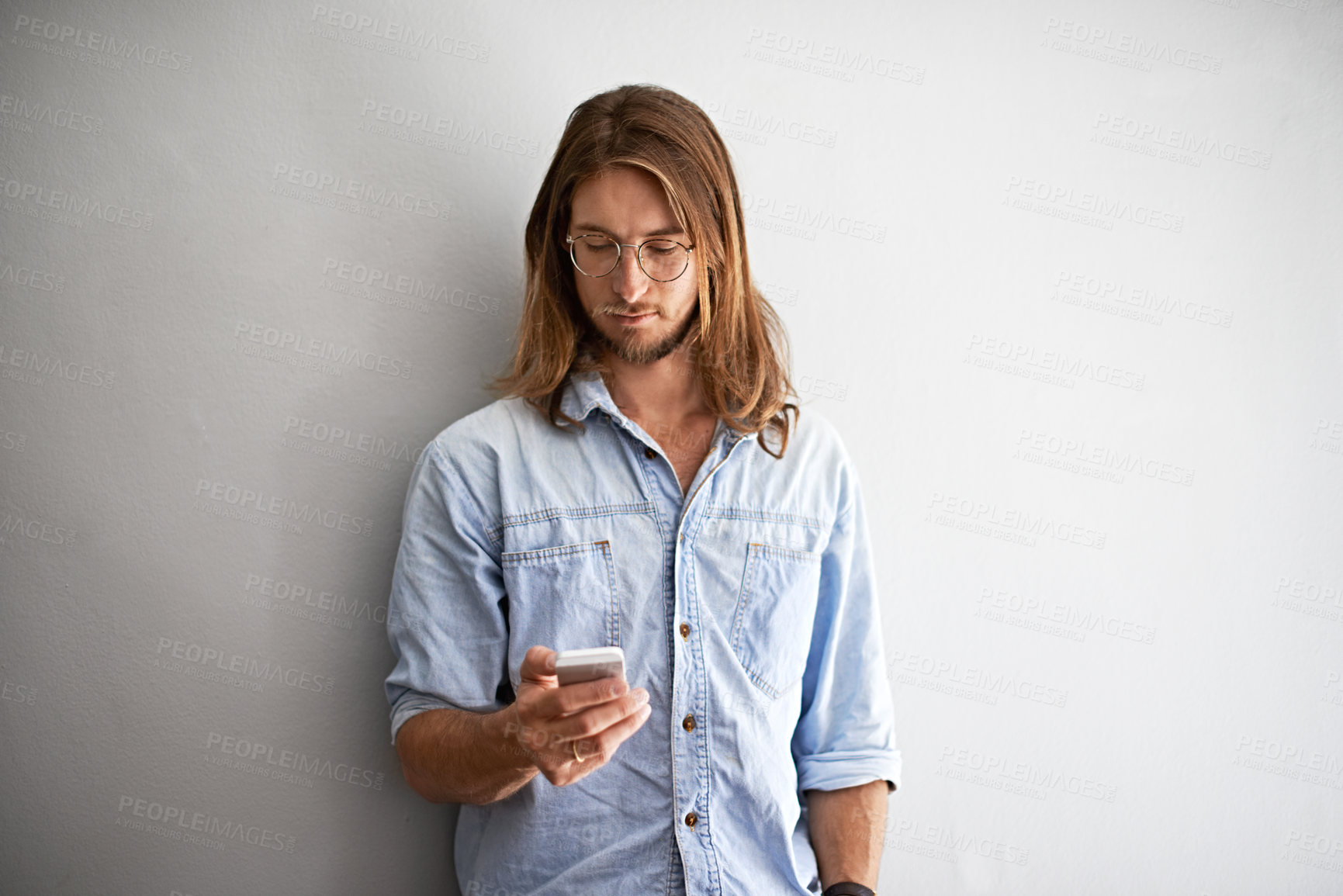Buy stock photo Studio shot of a young man using a cellphone against a gray background