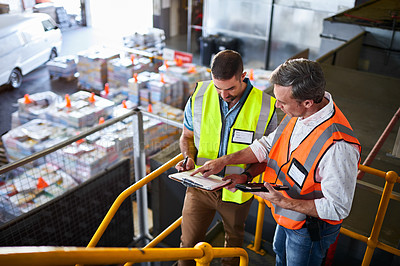 Buy stock photo Shot of two warehouse workers standing on stairs using a digital tablet and looking at paperwork