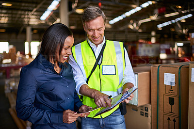 Buy stock photo Shot of two warehouse workers using a digital tablet and looking at paperwork