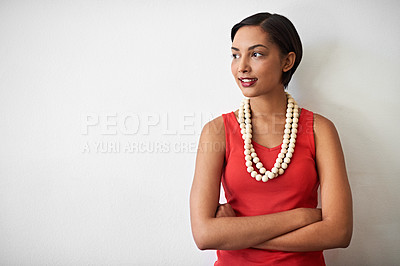 Buy stock photo Studio shot of a smiling young woman standing with her arms crossed against a gray background