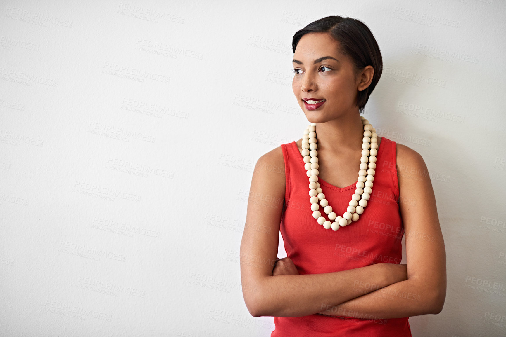 Buy stock photo Studio shot of a smiling young woman standing with her arms crossed against a gray background
