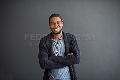 Buy stock photo Studio portrait of a smiling young man standing with his arms crossed against a gray background