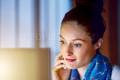 Buy stock photo Shot of a young woman working on her computer in an office late in the evening