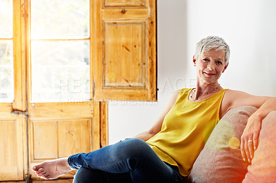 Buy stock photo Portrait of a smiling mature woman relaxing on her sofa at home