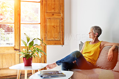 Buy stock photo Shot of a smiling mature woman relaxing on her sofa at home