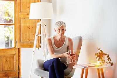 Buy stock photo Portrait of a smiling mature woman relaxing on a chair at home with a glass of wine