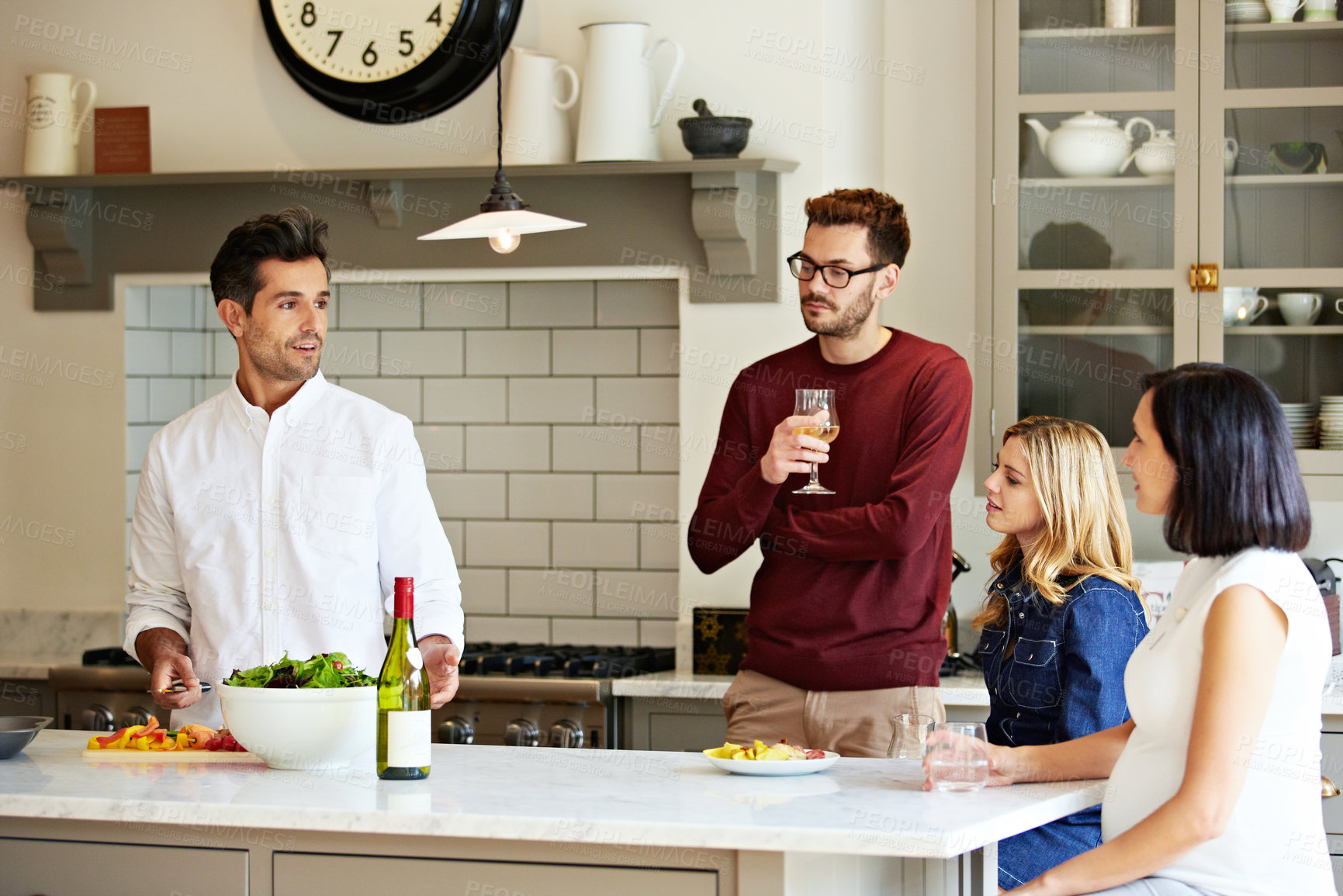 Buy stock photo Shot of a group of friends talking and drinking wine while preparing a meal together