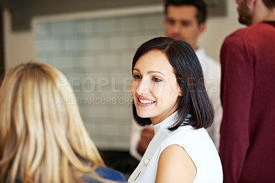 Buy stock photo Shot of a two young women talking together in a kitchen with their partners in the background