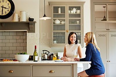 Buy stock photo Shot of two friends talking together while sitting in the kitchen at home