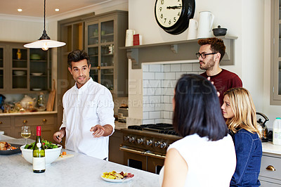 Buy stock photo Shot of a group of friends talking and drinking wine while preparing a meal together