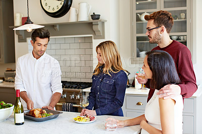 Buy stock photo Shot of a group of friends talking and drinking wine while preparing a meal together