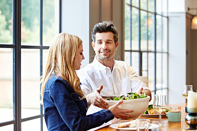 Buy stock photo Shot of a young couple enjoying a home-cooked dinner together