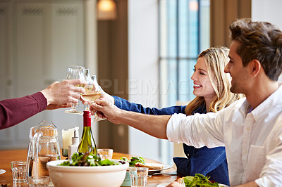 Buy stock photo Shot of a group of friends toasting while enjoying a home-cooked dinner together