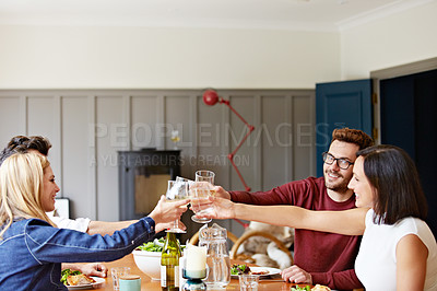 Buy stock photo Shot of a group of friends toasting while enjoying a home-cooked dinner together