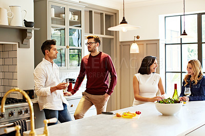 Buy stock photo Shot of a group of friends talking and drinking wine while preparing a meal together