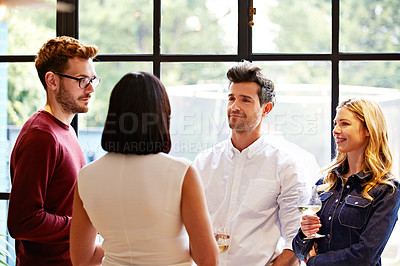 Buy stock photo Shot of a group of friends drinking wine and talking together in a kitchen at a get-together